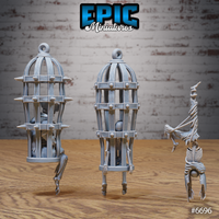 Rear and side view of the same three Epic Miniatures skeleton cage scatter pieces — showing the spiked iron cage and ribbed birdcage from behind, both with skeletal occupants visible through the bars, alongside the handstand skeleton, all in unpainted grey resin on a wooden surface