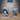Two unpainted grey resin scatter terrain pieces by Epic Miniatures — a skull-encrusted dead tree with grasping skeletal limbs on the right, and a feathered dome shrine with hanging tendrils and skull-carved base on the left, photographed together on a wooden surface
