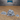 Three grey resin scatter terrain pieces from Epic Miniatures showing a large mound of tangled skeletal remains, a low pile of skulls, and a small bone scatter — all unpainted and viewed from a slightly elevated angle on a wooden surface