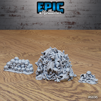 Three grey resin scatter terrain pieces from Epic Miniatures showing a large mound of tangled skeletal remains, a low pile of skulls, and a small bone scatter — all unpainted and viewed from a slightly elevated angle on a wooden surface