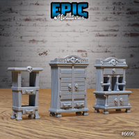 Three unpainted grey resin gothic wardrobe scatter terrain pieces from Epic Miniatures — a tall double-door wardrobe with skull cornice and bone handles, a wide chest-of-drawers with open cabinet and skull details, and a slim pedestal side-table, all decorated with carved woodgrain, skull finials, and crossbone hardware, shown from the front