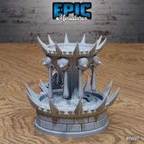 Rear three-quarter view of the unpainted grey resin Blood Fountain terrain piece by Epic Miniatures — showing the full spiked lower basin, weeping skull pillars, and decorative scrollwork on the cylindrical stone drum base, printed by Mitz and Simz