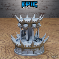 Rear three-quarter view of the unpainted grey resin Blood Fountain terrain piece by Epic Miniatures — showing the full spiked lower basin, weeping skull pillars, and decorative scrollwork on the cylindrical stone drum base, printed by Mitz and Simz