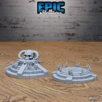 Two unpainted grey resin occult terrain pieces by Epic Miniatures: a horned skull shrine with stepped base and candles on the left, and a circular pentagram summoning dais ringed with candles on the right, photographed on a wooden surface