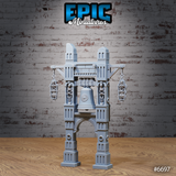 Unpainted grey resin bell ruins terrain piece showing the ornate central bell, two skeleton figures locked into the main pillar alcoves, and two caged skeleton lanterns suspended from crossbeams — slightly elevated front view