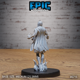 Rear view of the same unpainted grey resin Novice Lich miniature showing a billowing open coat with detailed hem and fabric folds, one hand raised with a small flame effect, small horned crest visible from behind, on a flame-tendril base