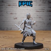 Front view of an unpainted grey resin 32mm Novice Lich miniature by Epic Miniatures — hooded skeletal spellcaster in layered occult robes, raising one hand wreathed in spectral flame while holding an ornate staff low in the other, mounted on a medium 25.5mm round base