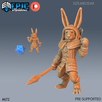 Digital render of a 32mm harengon spearman miniature by Epic Miniatures, shown from front and back. The character wears a hooded cloak, buckled armour with wrapped strapping, and carries a long spear angled low in a forward guard. A blue d20 is shown for scale. Unpainted resin render in warm tan tone.