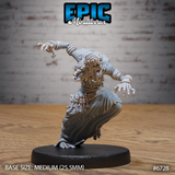 Unpainted grey resin Ghoul Gravecaller miniature by Epic Miniatures, shown from the front — a hunched undead female figure lunging forward in a dynamic crouch, one clawed arm outstretched, wearing tattered robes with bone fetishes at her belt and wrist wrappings, a crown of dried flowers tangled in her long hair, mounted on a medium 25.5mm round base