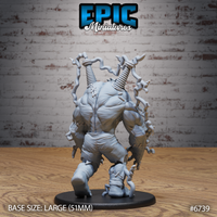 Rear view of the Electric Frankenstein resin miniature showing scarred, straining musculature, twin coil bolts buried in his back, and chain tendrils spiralling outward, with torn bandaged legs and a secondary figure pinned beneath his foot on a 51mm base