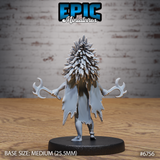 Rear view of the unpainted grey resin Amazoness Raven Cleric miniature, showing the dense overlapping feather texture of the headdress from behind, the ragged hem of the tunic, and the twin crescent blades held at each side, mounted on a medium 25.5mm black base