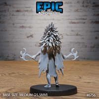 Rear view of the unpainted grey resin Amazoness Raven Cleric miniature, showing the dense overlapping feather texture of the headdress from behind, the ragged hem of the tunic, and the twin crescent blades held at each side, mounted on a medium 25.5mm black base