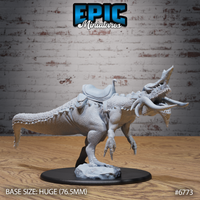 Front three-quarter render of the saddled variant of the Boneskull Rex unpainted grey resin miniature by Epic Miniatures — identical sculpt to the standard version but with a detailed leather riding saddle strapped across the creature's back, suitable for a mounted rider, on a Huge 76.5mm round base