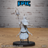 Rear view of the same horned female avatar miniature — long flowing hair cascades down her back, layered robes and split cloak shown in detail. Staff with ornate spiked crossguard gripped in one raised hand, opposite arm extended behind her. Sculpt by Epic Miniatures.
