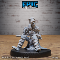 Seated female elf barbarian holding a long staff across her lap, wearing fur mantle, bead necklaces, and rope-wrapped leg armour, hair in an elaborate topknot. Sculpt by Epic Miniatures.