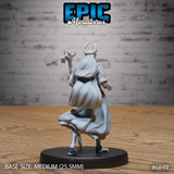 Antlered druid figure seen from behind, long hair spreading across shoulders, gnarled staff raised above head, wide flowing robes with sculpted movement at the hem, standing on a round base. Sculpt by Epic Miniatures.