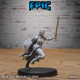 Female armoured knight mid-stride seen from behind, longsword raised overhead, rounded shield at her back, long cape billowing behind her with sculpted stitched edges. Sculpt by Epic Miniatures.