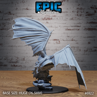 Dragon sculpt seen from behind and to one side, showing the broad membrane wings swept back, spined shoulders, and thick coiling tail beside the craggy rock base. Epic Miniatures.