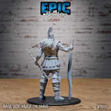 Heavily muscled Storm Giant seen from behind, long hair cascading beneath a crested plumed helmet, scaled pauldrons and armour visible across the back, holding a jagged lightning bolt in one hand and a large curved greatsword in the other. Sculpt by Epic Miniatures.
