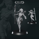 Close-up of an unpainted grey resin Amazon spear-bearer miniature by Galaad Miniatures — shown from front and rear on a round black base. She strides forward with a tall war spear, a quiver of arrows across her back, a skull motif on her leg armour, and feathered crest on her head. 32mm scale.