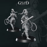 Front and rear views of an unpainted grey resin Amazon warrior miniature by Galaad Miniatures on round black bases — she carries a coiled rope in one hand and a heavy club in the other, wearing a tall feathered headwrap, layered wrappings on her legs, and a necklace of bones. 32mm scale.