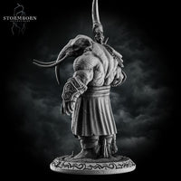 Rear view of the unpainted grey resin loxodon miniature showing thick hide texture across the back, wide-set tusks, and the runic text around the base, with the scythe blade visible over the left shoulder