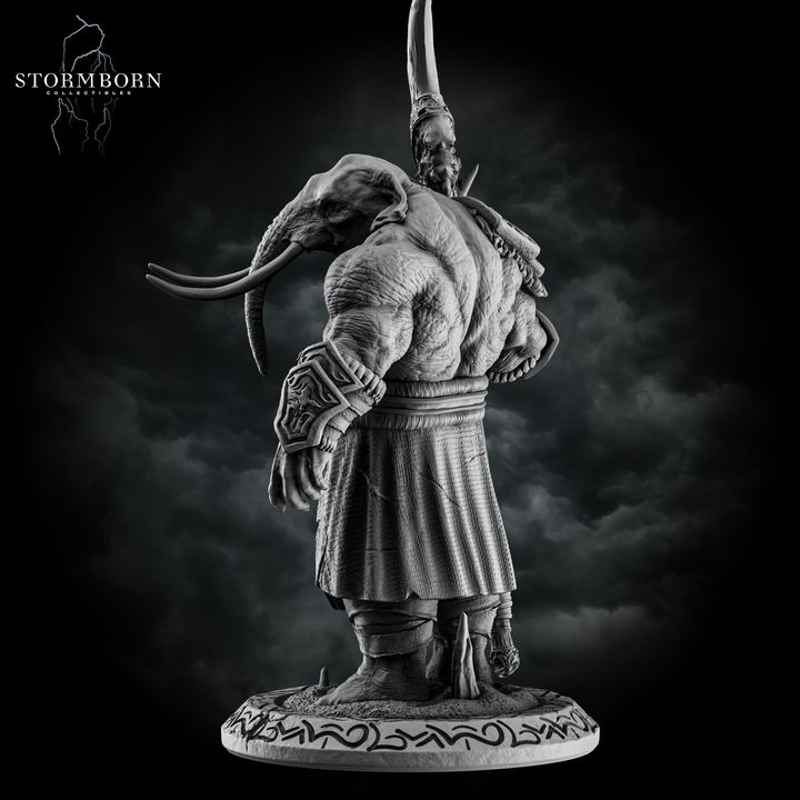 Rear view of the unpainted grey resin loxodon miniature showing thick hide texture across the back, wide-set tusks, and the runic text around the base, with the scythe blade visible over the left shoulder