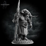 Three-quarter front view of the unpainted grey resin loxodon miniature with head bowed, gripping the ornate staff weapon with both hands, showing the full detail of the robes, medallion belt piece, and carved base