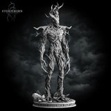 Digital render of an unpainted grey Treant miniature from Stormborn Collectibles — straight-on front view showing full skeletal bark torso, gnarled branch arms, and pointed antler head crown against a stormy background
