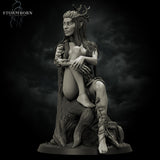 Grey resin digital render of Eva the Dryad miniature, front view — a seated female fey figure with an antler and oak leaf crown, long flowing hair, leaf-wrapped arms and calves, resting against a gnarled tree trunk with a climbing rose at her feet, on a textured round base