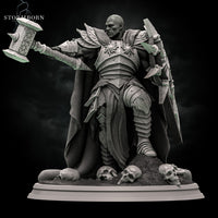 Rear view of an armoured warrior in layered plate with a heavy flowing cloak that drapes to the base, warhammer raised behind the shoulder, spiked pauldrons visible. Sculpt by Stormborn Collectibles.