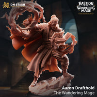 Digital render of Aaron Drafthold the Wandering Mage miniature — an unpainted resin figure of a bearded male mage with a top-knot, holding an open spellbook wreathed in flame, with a large ring of fire swirling around his raised left hand, standing on a rocky base