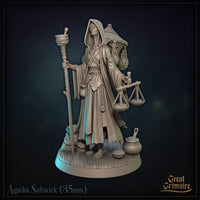Agatha Saltwick miniature facing forward: hooded elderly woman gripping a staff in one hand and a merchant's balance scale in the other, with sacks and pots at her feet. Sculpt by Great Grimoire.
