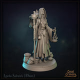 Agatha Saltwick miniature seen from behind: enormous woven basket on her back topped with a mortar and pestle, pouches hanging from netting, staff held at her side. Sculpt by Great Grimoire.