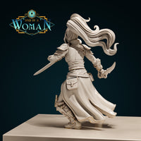 Rear view of an armoured female rogue, long hair streaming behind her, a longsword extended to the left, a curved short blade raised in her right hand, belted coat flowing mid-stride, detail visible on greaves and back pouches. Sculpt by DnD Is A Woman.