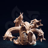 Unpainted resin miniature of Algaira the five-headed desert hydra, front view — showing five distinct serpentine necks rising from a coiled scaled body, with detailed overlapping scale plates, barbed horns, and open jaws, mounted on a round base