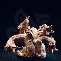 Unpainted resin miniature of Algaira the five-headed desert hydra, front view — showing five distinct serpentine necks rising from a coiled scaled body, with detailed overlapping scale plates, barbed horns, and open jaws, mounted on a round base