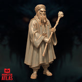 Elderly bearded wizard in flowing robes and turban, clutching a gnarled staff with an orb finial, sandalled feet visible beneath wide hems. Weathered, scowling face with deep-set eyes. Sculpt by Monster Atlas.