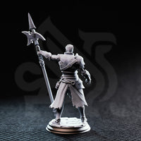 Rear three-quarter view of unpainted grey resin Andrek Strongarm miniature showing cross-braced back armour straps, scarred leather panels, the full length of the glaive shaft raised overhead, and the detailed texture of his ragged kilt