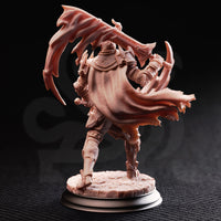 Rear view of the same unpainted resin Arcane Armour warrior miniature, showing the billowing tattered cape with detailed fabric folds, engraved back plate armour, and the twin serrated scythe-axe blades arcing above the figure against a dark background