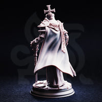 Rear-view photograph of the unpainted Arch Paladin Tyrius III miniature, showing the dramatic sweep of his full-length cloak, the back of his spiked pauldrons, and the detailed rubble base. The reliquary mace staff is visible at his side.