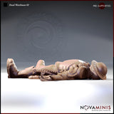 Digital render of Dead Watchman 02 miniature by Novaminis — a prone male human guard lying face-up, wearing studded leather armour with rivet and cross-lace detailing, brimmed iron helmet resting beside his turned head, one arm outstretched with open upturned hand, sturdy thick-soled boots visible at the far end, unpainted resin render in warm tan tones