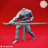 Unpainted grey resin render of Blemmye 03 miniature by Yasashii Kyojin Studios — a headless muscular warrior in a wide combat stance gripping a long barbed spear horizontally, frayed cord ankle bindings and clawed bare feet visible, face set into the chest with heavy brow and tusked jaw, viewed from the front-left