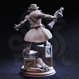 Photograph of the unpainted grey resin Brains goblin gangster miniature from the rear — showing the long flowing coat with visible wear lines, wild hair beneath the top hat, the blunderbuss raised in the right hand, and the reverse of the TNT crate base including a sack on the ground and additional crate detail