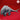 Unpainted grey resin Bulette miniature from Yasashii Kyojin Studios, viewed from the rear-left angle, showing large overlapping dorsal fins, segmented armoured back, muscular clawed legs, and a shark-like tail fluke — set against a red background