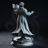 Carina Braithwaite miniature by DM Stash — front view showing raised casting hand with splayed fingers, open filigree-paged tome, tailored coat with leather belt, and scrollwork cloak fanning behind her.