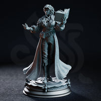 Carina Braithwaite sorceress miniature by DM Stash — one hand raised mid-cast, other hand holding an open tome, wearing a belted greatcoat and sweeping embossed cloak, on a detailed arcane base.