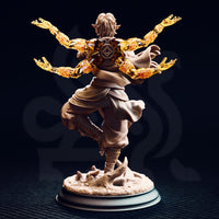 Rear view of the unpainted Caryian resin miniature showing the ornate eye-in-diamond back armour medallion, four golden astral flame arms spreading wide, billowing cape detail, and the sandy base with clawed emerging forms