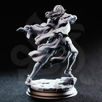 Rear three-quarter view of unpainted grey resin Cerindelia of House Verani miniature, showing the flowing coat detail, textured fabric panels, back armour plating, streaming hair, and shattered stone base