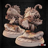 Two renders of the Clockwork Anglerfish by Mia Kay M3DM side by side — a bulbous mechanised fish body covered in overlapping scales and riveted plating, wrapped in heavy chains, with a curved pipe lure rising from the top. Wide open jaws lined with jagged teeth, fanned fin-like exhaust vanes at the sides, and a textured industrial base with small pipe stubs.